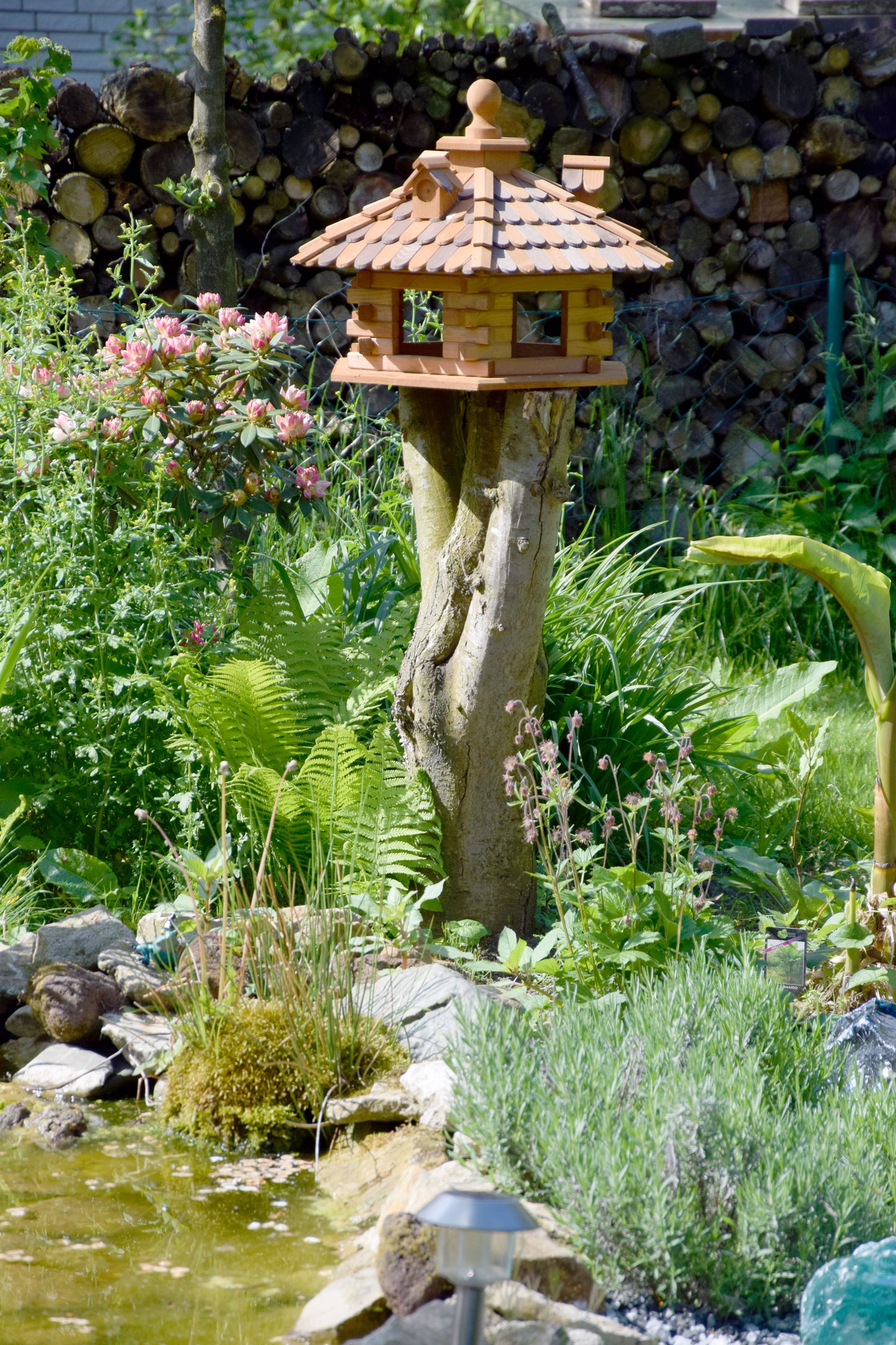 Rustikales, sechseckiges Vogelhaus aus massivem Kiefernholz mit dekorativen Dachgauben und Holzschindeldach, perfekt für die Fütterung von Wildvögeln.