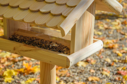 Detailreiches Vogelhaus aus imprägniertem Kiefernholz mit schützendem Futtersilo und dekorativem Holzschindeldach.