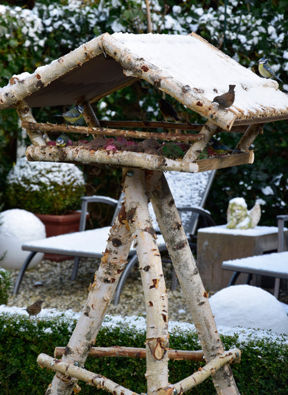 Handgefertigtes Vogelfutterhaus mit robustem Birkenholz und Rinde, ideal für Wildvögel im Garten.
