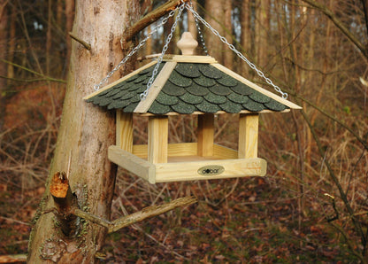 Klassisches Vogelfutterhaus aus imprägniertem Holz mit Metallkette zum Aufhängen an Bäumen und Wänden.
