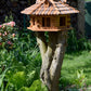 Großes Vogelhaus mit sechseckigem Design und Holzschindeldach, bietet mehreren Wildvögeln gleichzeitig einen Futterplatz.