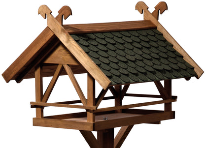 Detailansicht des großen Vogelfutterhauses mit grünem Bitumendach und rustikalem Design.
