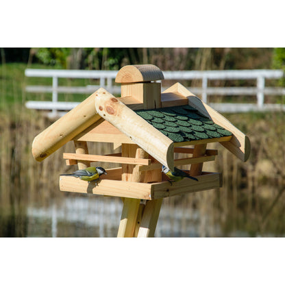Massives Vogelfutterhaus aus imprägniertem Kiefernholz mit grünem Bitumendach und praktischem Futtersilo, montiert auf einem Ständer.